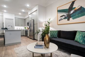 a living area with a couch coffee table and a kitchen in the background